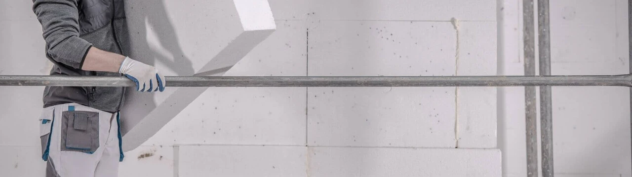 polystyren-zateplenie.jpg Robotník drží biely polystyrén na zateplenie na lešení