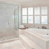 Kúpeľňa so spchovým kútom a vaňou s bielym obkladom a dlažbami